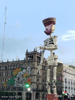 Ofrenda Monumental de Día de Muertos 
Consta de 21 piezas de cartonería monumental que van de los seis a los 10 metros de altura, una ofrenda monumental de 17 metros de altura, con un espejo de agua de más de 200 metros cuadrados, dos trajineras y una chinampa monumental, un jardín de cempasúchil con 10 mil plantas de productores y productoras de Xochimilco.

Text and Photo by: Yanín Ramírez
Keywords: ofrenda monumental dia muertos pan de muerto zocalo iluminado calacas cartoneria